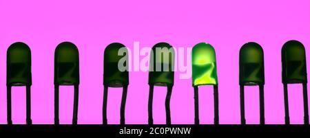 Single diode glowing in a row of LED's isolated on pink purple background. Thinking outside the box concept. Stock Photo