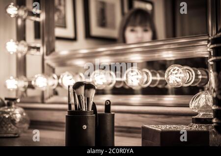 vintage vanity makeup accessories, makeup dressing table with undefined woman at mirror Stock Photo
