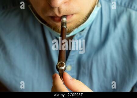 Man holding vintage smoking pipe in hand. Male smoking tobacco. Stock Photo