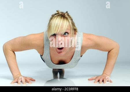 blond sportive woman is doing push-ups with a funny face Stock Photo
