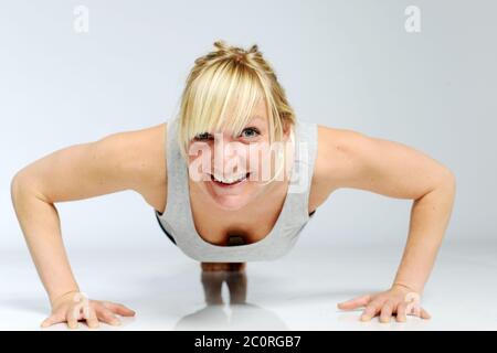blond sportive woman is doing push-ups with a funny face Stock Photo