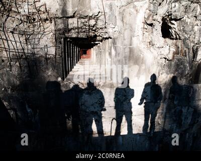 Loophole in old military bunker and shadows of men on devasted wall Stock Photo