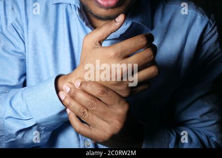 Young man in blue shirt suffering wrist pain  Stock Photo