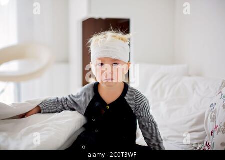 Little toddler boy with head injury, lying in bed, tired, sleeping Stock Photo