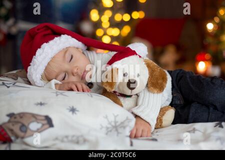 Sweet beautiful blond toddler boy, sleeping in bed with toy on Christmas Stock Photo