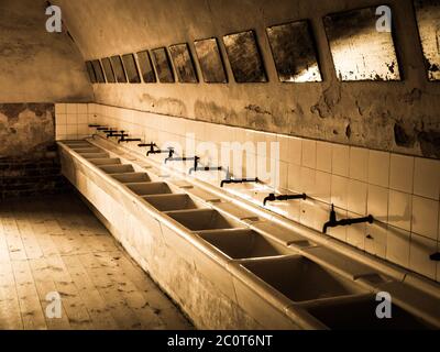 Row of sinks and mirrors in old prison bathroom, sepia image Stock Photo