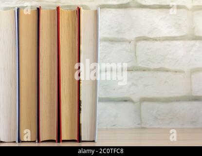 Books stand on a shelf or table against the wall. Stock Photo