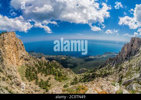 Scenic panoramic high angle view from top of Ai-Petri mountain towards coastline between Yalta and Alupka with clouds in morning sunlight, Crimea, Rus Stock Photo