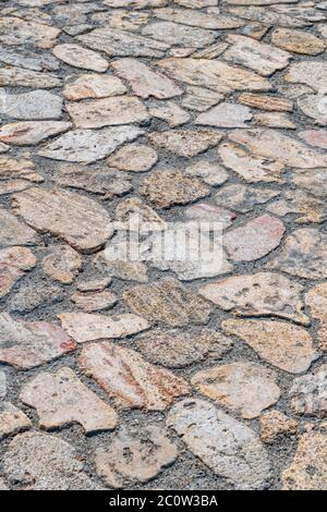 The road paved from wild paving stones of various shapes. Wild stone pavement floor. Irregular shapes pattern Stock Photo