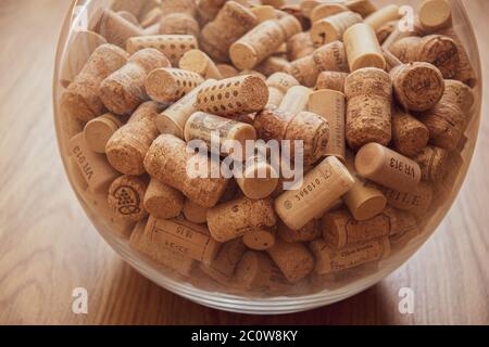 Sphere shape glass vase fill with many used wine corks on wooden background. Pile of various bottle stoppers for winery concept background Stock Photo