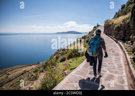 backpacker woman walking on trail in al island by a lake titicaca a huge beautiful lake Stock Photo