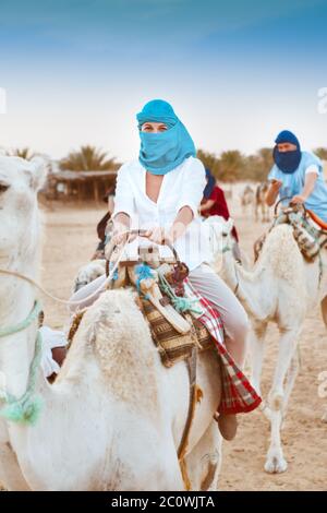 Young caucasian woman tourist riding on camel in Sahara desert Stock Photo