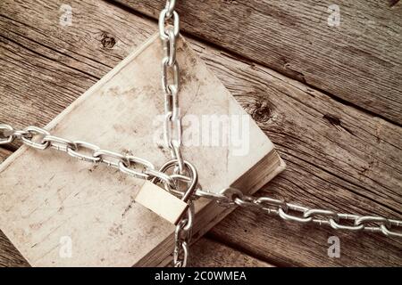 Chained book on wooden background