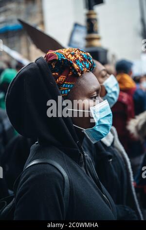 London / UK - 06/06/2020: Black Lives Matter protest during lockdown coronavirus pandemic. Beautiful black female protester wearing blue medical mask Stock Photo