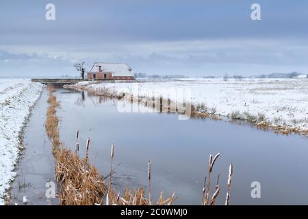 house by river in snow on Dutch farmland Stock Photo