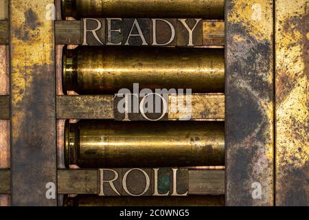 Photo of real authentic typeset letters forming Ready to Roll text on vintage textured silver grunge copper and gold background Stock Photo
