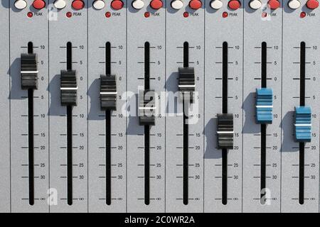 Sound mixing desk faders. Music studio recording equipment volume close-up image with peak LED and stereo master sliders. Home recording for musicians Stock Photo