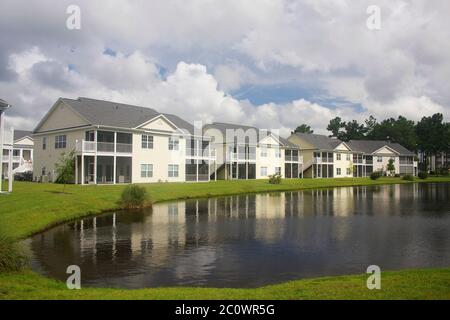 Southern residential neighborhood. Background with a modern neighborhood with buildings around the pond. Houses and trees reflected in the tranquil wa Stock Photo