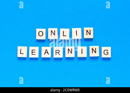 online learning concepts written in wooden letters on a blue background. a top view of a flat layout, online school. a new form of learning Stock Photo