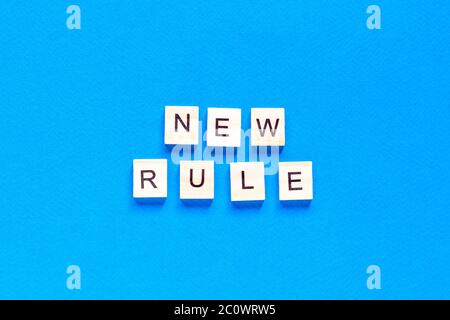 The NEW RULE is written in wooden letters on a blue background. New concept. Business, law, rules, update. tflat layout. op view. Stock Photo