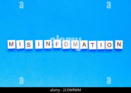 mystification written in wooden letters on a blue background, top view, deception, fake information, fake news, flat layout Stock Photo