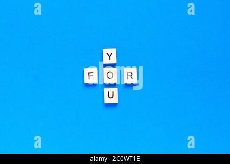 FOR YOU written in wooden letters on a blue background. top view, flat layout. Stock Photo