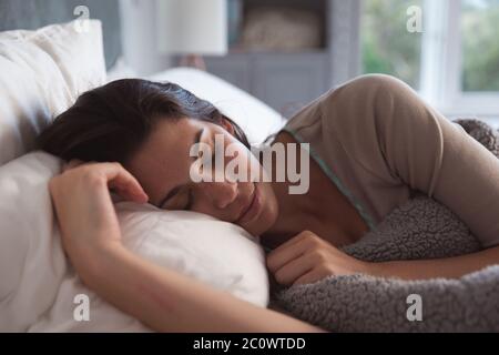 Mixed race woman lying on bed during coronavirus covid19 pandemic Stock Photo