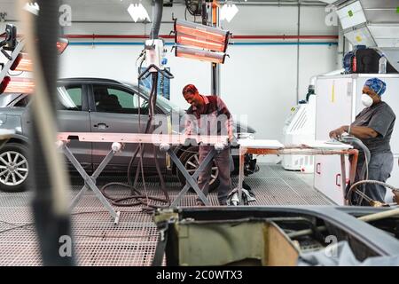 Happy multi races mechanics sanding and drying car pieces Stock Photo