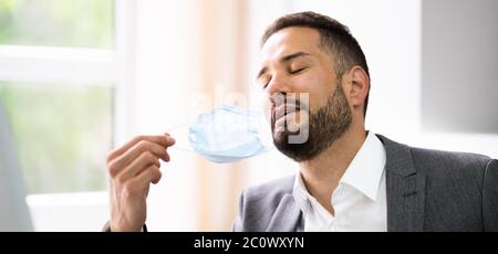 Man Removing Face Mask To Breath Freely Stock Photo