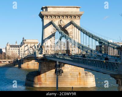 Massive pillar of Szechenyi Chain Bridge over Danube River joins Buda and Pest side of Budapest the capital city of Hungary, Europe. Suspension type of a bridge on sunny day with clear blue sky background. Stock Photo