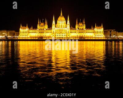 Night view of illuminated historical building of Hungarian Parliament, aka Orszaghaz, with typical symmetrical architecture and central dome on Danube River embankment in Budapest, Hungary, Europe. It is notable landmark and seat of the National Assembly of Hungary. Stock Photo