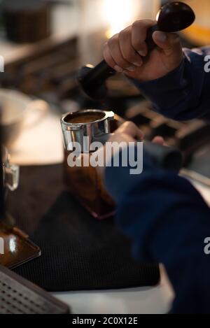 Barista presses ground coffee using tamper. Making Espresso Stock Photo