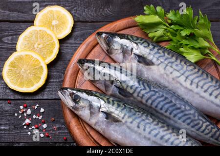 Top view composition of mackerel on wooden cutting board with salt, pink pepper, parsley and lemon Stock Photo