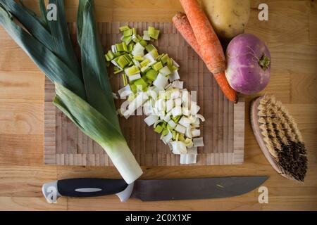 Top view of a cutting board, winter vegetables a brush and a knife on a wooden table Stock Photo