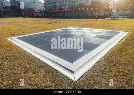 Wide-angle view of a huge rectangular air shaft outdoors leading to metro or an underground facility with a striped square metal grills on the top Stock Photo