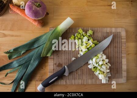 Top view of a cutting board, winter vegetables a brush and a knife on a wooden table Stock Photo