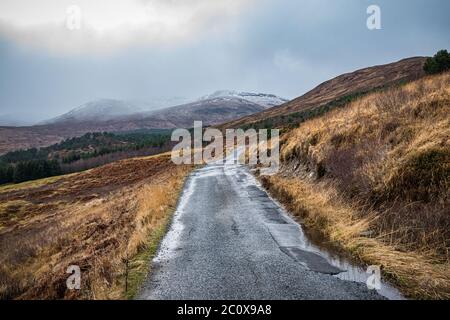 Single track road in Glen Lyon, Scottish Highlands. Winter landscape of Glen Lyon, Scotland on an overcast day. Stock Photo