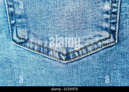 Close-up pocket of denim blue fabric with yellow seams. Fashionable jeans. View from above. Stock Photo