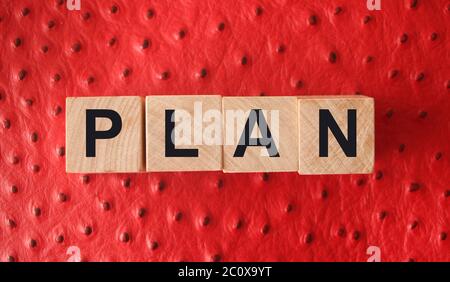 Wooden Blocks with the text: Plan on red leather background. Business planning management concept