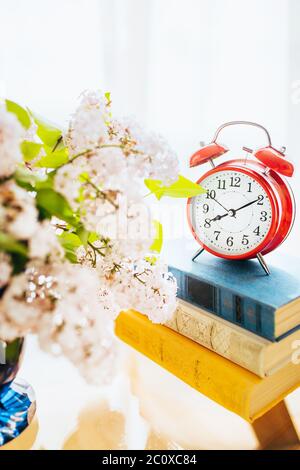 8 hours and 10 minutes on a red table clock with an alarm clock - a stack of books for the morning lesson Stock Photo