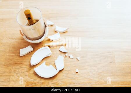 Broken ceramic jar on the table a lot of fragments - the punishment for sloppiness - copy space Stock Photo