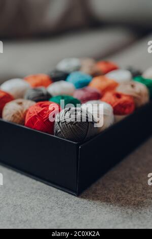 Close up of a box full of amigurumi cotton dk yarn in different colours, selective focus on the closest skein. Stock Photo