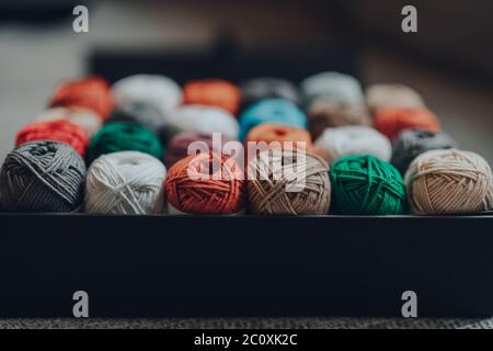 Close up of a box full of 24 different coloured skeins of amigurumi cotton yarn, selective focus on the closest row. Stock Photo