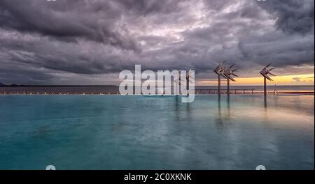 Storm clouds brewing at sunrise on the Cairns Esplanade public swimming lagoon on the edge of the Great Barrier Reef in Queensland, Australia. Stock Photo