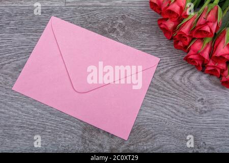 Pink envelope and roses on a wooden background Stock Photo