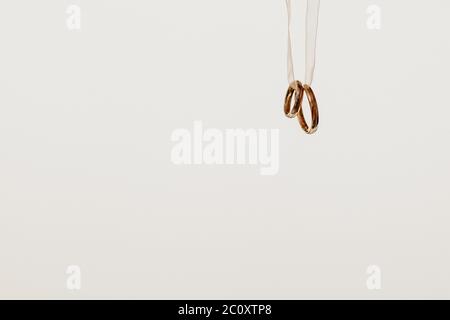 Two golden wedding rings hanging on a ribbon, isolated on white background Stock Photo