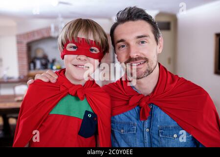 Portrait of father and son pretending to be superhero in living room Stock Photo