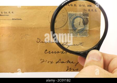 An old postage stamp honoring Benjamin Franklin under a magnifying glass. Stock Photo