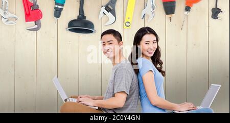 Composite image of portrait of young happy couple using laptop while sitting Stock Photo