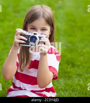 Portrait of a pretty little girl smiling and holding retro camera Stock Photo